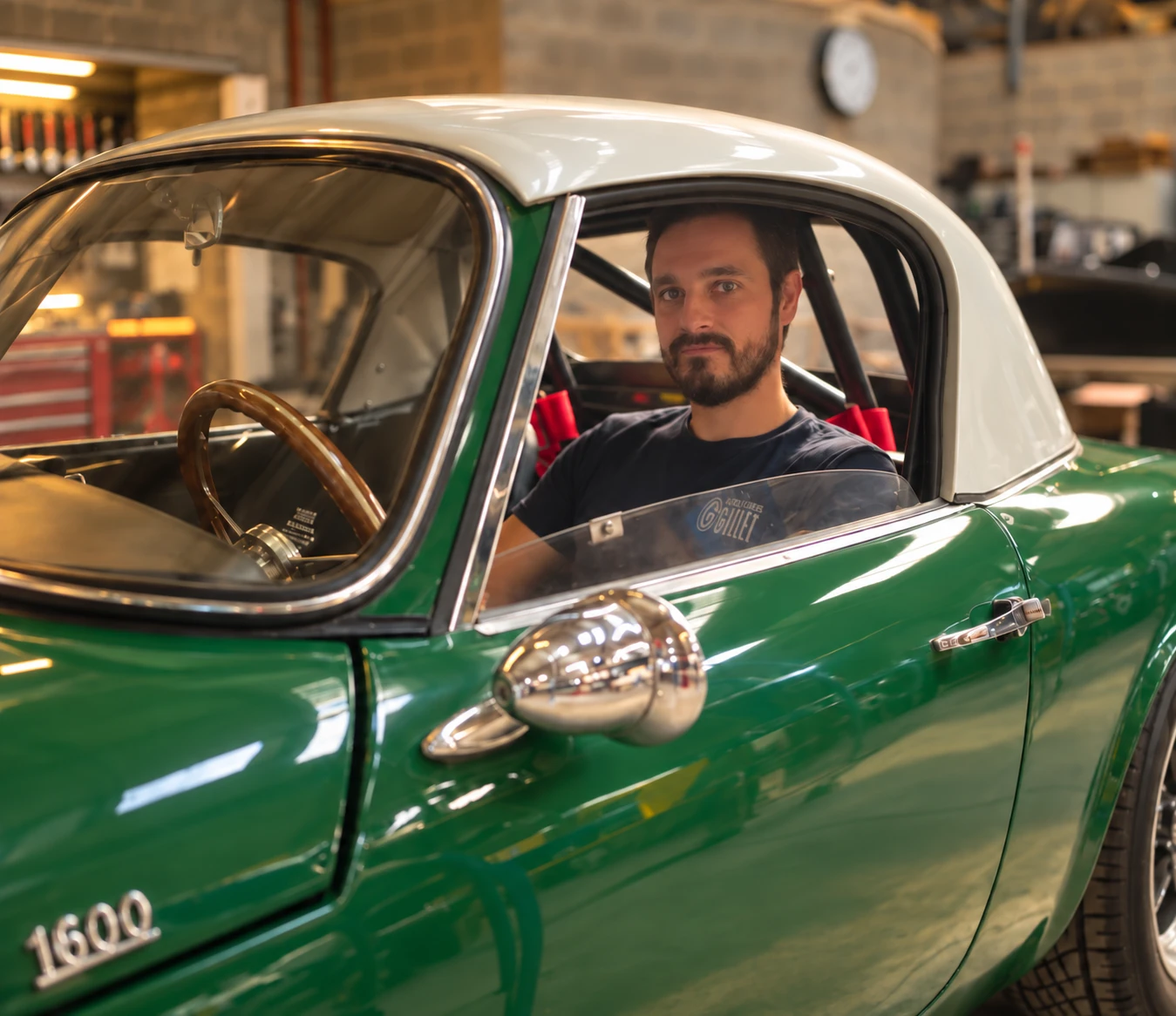 Timothy Dehan au volant d'une Lotus Elan 1600 verte, dans l'atelier